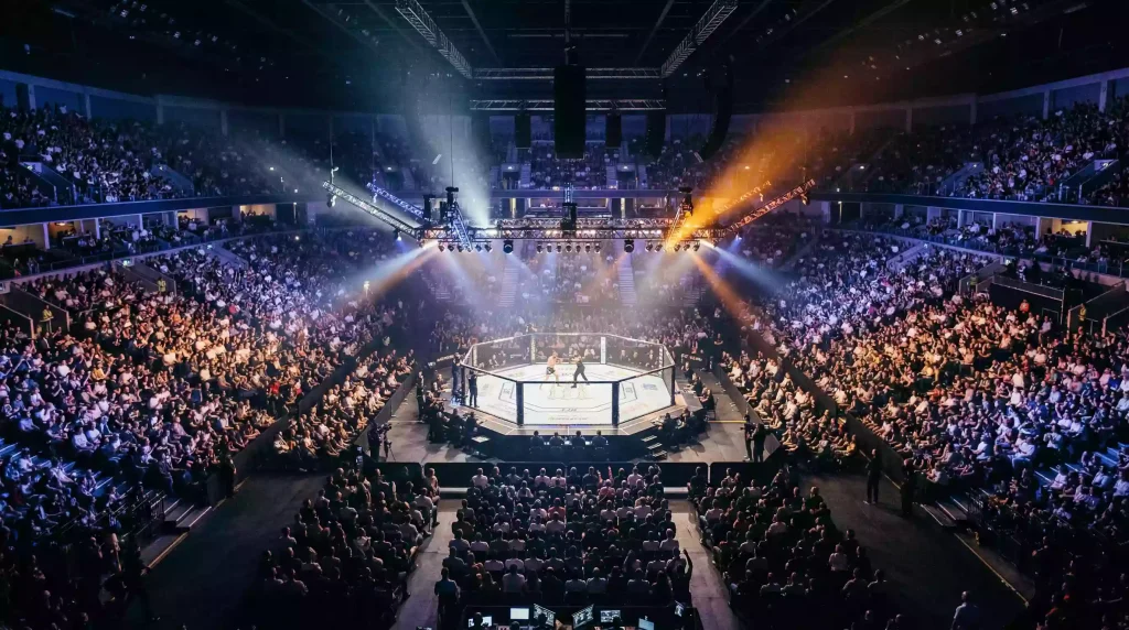 Público multitudinario en un evento de UFC con las luces del estadio iluminando el octágono