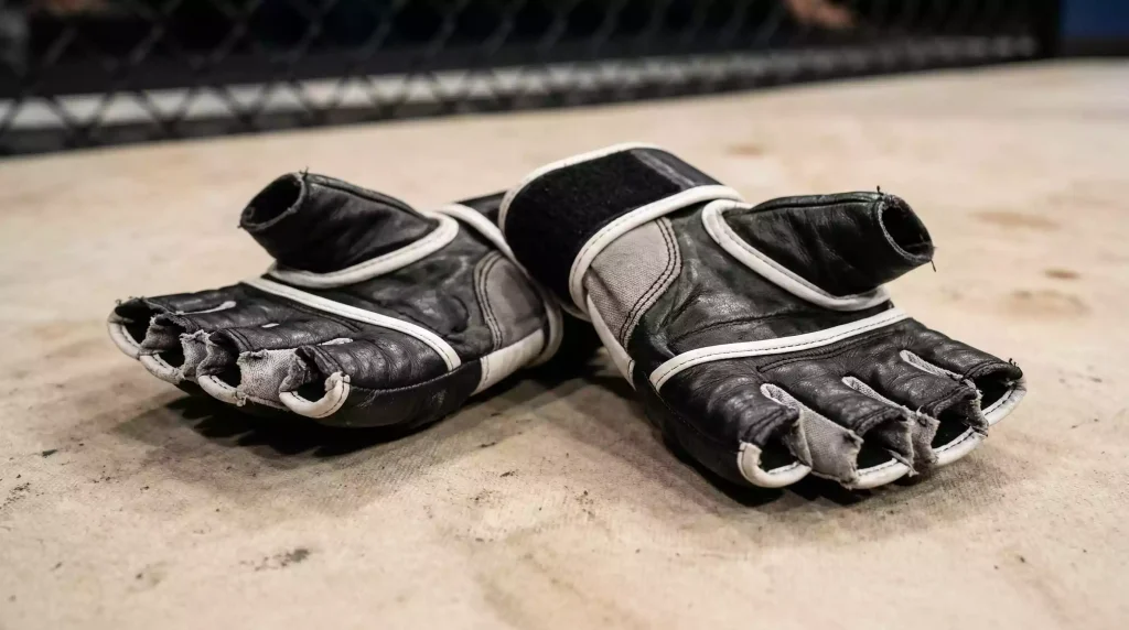 Primer plano de guantes de MMA sobre la lona del octágono con iluminación de evento UFC