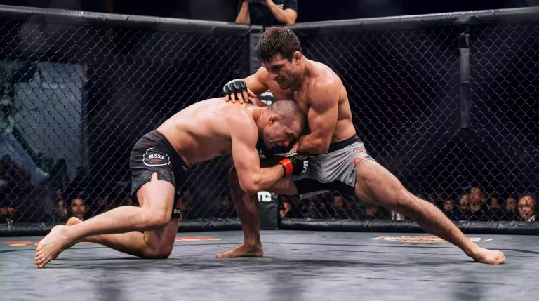 Luchador de MMA ejecutando un derribo sobre su oponente en el octágono durante un combate profesional
